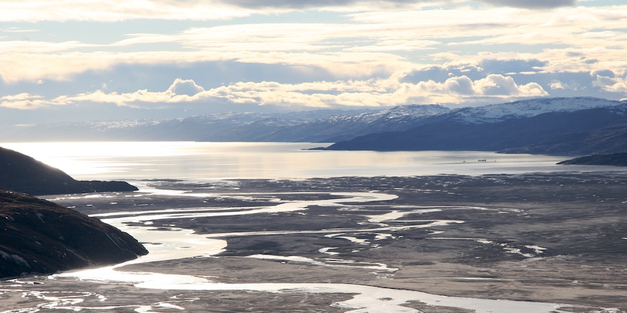 A container ship bringing supplies to the natives of Greenland is dwarfed by the immense landscape of Søndre Strømfjord.