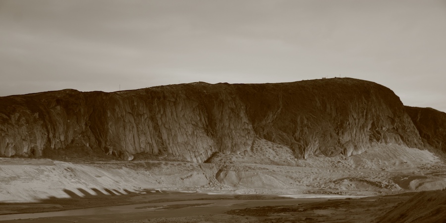 Long shadows are cast from the Søndre Strømfjord outpost dormitories onto the base of Raven's Cliff.