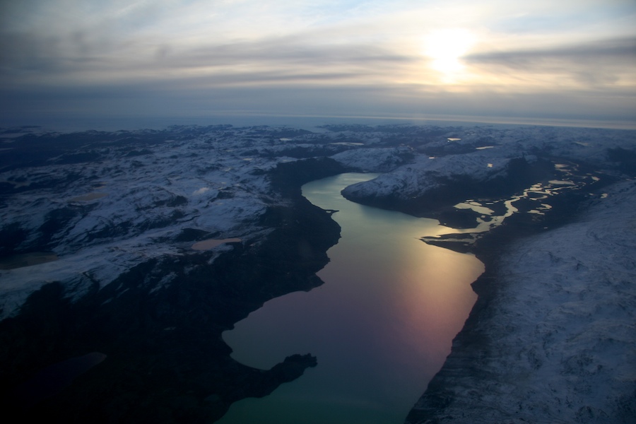 The serenity of a smooth glacial lake at dawn in an otherwise jagged arctic landscape.